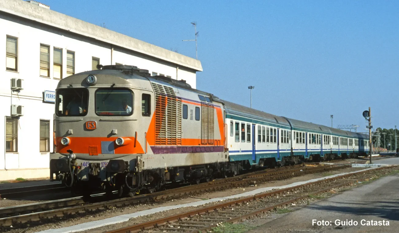 Locomotiva diesel D.445 di prima serie delle FS nella livrea Navetta, con i colori grigio, arancio e viola al traino di un treno regionale con carrozze MDVC, Pitzalis Modellismo